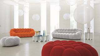 Zwei Roche Bobois Sofas in orange und weiß mit je einem Hocker in weiß und rot  in einem weißen Raum mit Luftballons